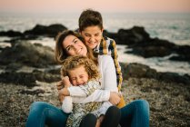 Middle aged woman with her children at sea shore smiling and hugging each other — Stock Photo
