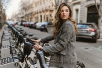Lady choosing rental bicycle on parking lot — Stock Photo