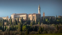 Veduta dell'antica cattedrale tra i cipressi verdi della campagna toscana — Foto stock