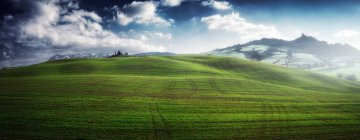 View of beautiful endless green fields in bright sunlight under cloudy sky, Italy — Stock Photo