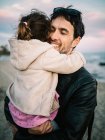 Мила сцена тата тримає і обіймає свою маленьку дочку на пляжі взимку — стокове фото