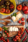 Fresh tomatoes and mozzarella cheese with basil leaves for salad on wooden board and fabric — Stock Photo