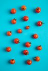 Fresh ripe tomatoes on scattered on blue background — Stock Photo