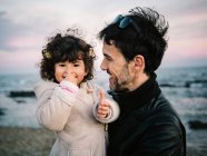 Cena fofa de pai segurando e abraçando sua filhinha na praia no inverno — Fotografia de Stock