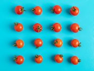 Frische reife Tomaten auf blauem Hintergrund verstreut — Stockfoto