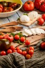 Tomates frescos e queijo mussarela com folhas de manjericão para salada em tábua de madeira e tecido — Fotografia de Stock