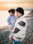 Милая сцена папа держит и обнимает свою маленькую дочь на пляже зимой — стоковое фото