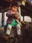 Lindo niño jugando con concha junto a un muelle en la playa - foto de stock