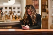 Весела жінка за допомогою смартфона в кафе — стокове фото