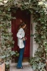 Stylish woman standing near red door — Stock Photo