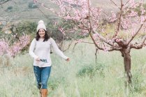 Viaggiatore femminile con libretto guida a piedi vicino agli alberi in fiore nella campagna primaverile — Foto stock