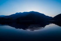 Pittoresca vista della superficie dell'acqua vicino a incredibili colline rocciose al tramonto e cielo blu — Foto stock