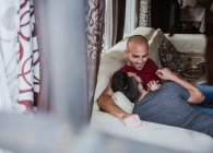 Romántico gay pareja relajante en sofá en casa - foto de stock
