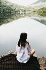 Жінка сидить на ковдрі біля озера і гір — стокове фото