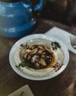 Cogumelos e hummus tradicional em chapa em mesa de madeira — Fotografia de Stock