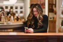 Feminino pensativo usando smartphone no café — Fotografia de Stock