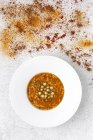 Traditionelle Harira-Suppe für Ramadan im Teller auf weißer Tischplatte mit verstreuten Gewürzen — Stockfoto