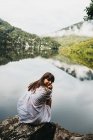 Жінка сидить на скелі біля озера і гір — стокове фото