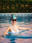 Jovem mulher chinesa rica relaxante nadando em uma piscina em um resort de luxo — Fotografia de Stock