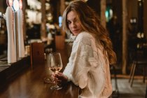 Stylish woman drinking wine at counter in bar — Stock Photo