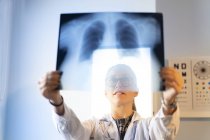 Крупный план женщины-врача в форме, смотрящей на рентгеновское изображение в комнате — стоковое фото
