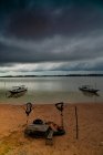 Традиционные лодки на песчаном пляже с спокойной водой под темным облачным небом, Камбоджа — стоковое фото