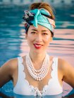 Jovem mulher chinesa rica relaxante nadando em uma piscina em um resort de luxo — Fotografia de Stock