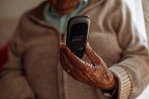Uomo anziano che usa il telefono all'interno della sua casa — Foto stock