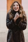 Elegante joven sonriente en abrigo de cuero vintage mirando a la cámara - foto de stock