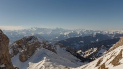 Vista panoramica del pendio innevato sullo sfondo delle montagne nella foschia e nella luce del sole, Svizzera — Foto stock