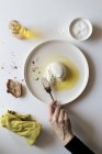 Mão de pessoa idosa anônima usando garfo para tomar pedaço de burrata fresca gostosa de prato perto de pão e óleo contra fundo branco — Fotografia de Stock