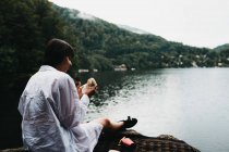 Женщина ест гамбургер возле озера и гор — стоковое фото