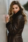 Sensual stylish woman in leather coat standing on street — Stock Photo