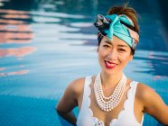 Mujer china rica joven relajándose nadando en una piscina en un resort de lujo - foto de stock