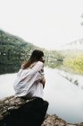 Femme assise sur le rocher près du lac et des montagnes — Photo de stock