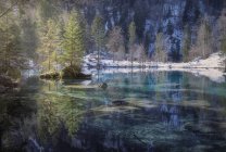 Paisaje de apacible lago azul con costa nevada en las montañas de Suiza - foto de stock