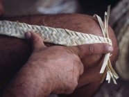 Mano de artesano anónimo usando gancho para tejer fibras secas de hojas de palma mientras trabaja en taller - foto de stock