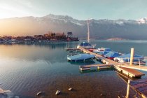 Пейзаж Тихого блакитного озера з невеликим пірсом і човнами на фоні гір на сонці, Швейцарія — стокове фото