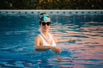Mujer china rica joven relajándose nadando en una piscina en un resort de lujo - foto de stock
