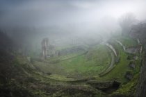 Dall'alto veduta delle rovine verdi muschiate nella nebbia pesante, Italia — Foto stock