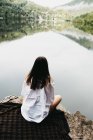 Жінка сидить на ковдрі біля озера і гір — стокове фото