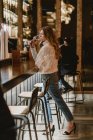 Stylish woman drinking wine near counter in bar — Stock Photo