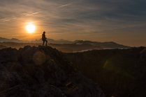 Silhouette eines Reisenden, der auf einer Klippe am Meeresufer gegen den Sonnenuntergang steht, Spanien — Stockfoto