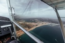 Aerial view of sea coast from inside a cabin of a small plane — Stock Photo