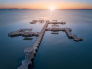 Вид з повітря на порожній дерев'яний геометричний пірс над тихою водою на яскравому фоні сонця — стокове фото