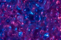 Von oben kleine rohe Welo-Opalsteine in einem Haufen unter blauem und rosa Licht platziert — Stockfoto