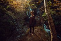 Rückansicht einer Frau in einem kleinen Fluss und Wasserfall fließt in grün dunkel schönen Wald. — Stockfoto