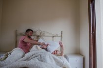 Verspieltes homosexuelles Paar, das morgens im Bett herumalbert — Stockfoto