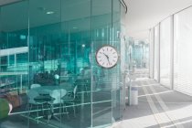 Conception d'un bureau moderne avec des murs transparents bleus et couloir lumineux avec horloge, Suisse — Photo de stock