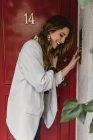 Stilvolle Frau steht vor roter Tür und lacht — Stockfoto
